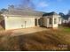 Spacious backyard with a concrete patio, lush green grass, mature trees, and a well-maintained home exterior at 6440 Tivoli Ct, Charlotte, NC 28211