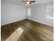 A simple bedroom featuring hardwood floors, freshly painted walls, natural light from two windows, and a ceiling fan at 6440 Tivoli Ct, Charlotte, NC 28211