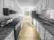 Galley kitchen featuring modern appliances, sleek countertops, white cabinetry, and durable hardwood floors at 6440 Tivoli Ct, Charlotte, NC 28211