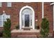 Elegant front entrance featuring an arched doorway, brick steps, and potted flowers at 6565 Derby Nw Ln, Concord, NC 28027