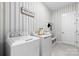 Well-equipped laundry room with modern appliances, stylish striped wallpaper, and convenient storage solutions at 6727 Baker Creek Ave, Indian Land, SC 29707
