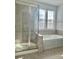 A bright bathroom featuring a tiled shower, a bathtub, and a window with blinds at 1019 Dunhill Ln, Waxhaw, NC 28173