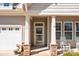 Close up of front porch featuring stone pillar bases, a glass door, sidelight windows, and white rocking chairs at 113 Artisan Ct, Mooresville, NC 28117