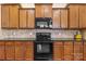 Well-lit kitchen featuring wooden cabinets, black appliances, and granite countertops at 113 Artisan Ct, Mooresville, NC 28117