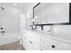 A modern bathroom featuring a large black framed mirror, white vanity, and a tub shower with white marble tiling at 13110 Blacksmith Ct, Matthews, NC 28105