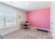 Bright bedroom with neutral carpet, a large window, and a modern desk with pink accent wall at 147 Colonial Reserve Ave, Troutman, NC 28166