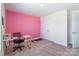 Spacious bedroom with a pink accent wall, neutral carpet, and a modern desk; exercise equipment at 147 Colonial Reserve Ave, Troutman, NC 28166