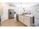 White kitchen features stainless appliances, granite counters, island with sink, and light wood flooring at 147 Colonial Reserve Ave, Troutman, NC 28166
