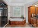 A soaking tub sits under a window in this bathroom with tile floors, a glass shower, and dark wood cabinets at 15015 Nc Hwy 73 Hwy, Huntersville, NC 28078