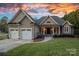 Charming home with a two-car garage, beautiful lawn, and inviting front entrance beneath a dramatic sunset sky at 15015 Nc Hwy 73 Hwy, Huntersville, NC 28078