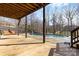 Covered deck featuring a wooden swing overlooking an in-ground pool and wooded backyard at 153 Byers Rd, Troutman, NC 28166