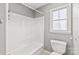 Bathroom with a white tub and shower, matching toilet, and natural light from a window at 2913 Ashley Woods Ct, Monroe, NC 28112
