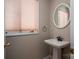 Cozy powder room featuring a pedestal sink, round mirror, and soft lighting at 8082 Golf Course N Dr, Denver, NC 28037