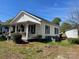 A side view of a charming white cottage features black shutters, a covered porch, and a well-maintained lawn at 1001 N Cannon Blvd, Kannapolis, NC 28083
