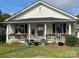 Charming white cottage with a covered porch adorned with flowers and seating creates a welcoming curb appeal at 1001 N Cannon Blvd, Kannapolis, NC 28083