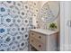 Stylish half-bathroom showcasing patterned wallpaper, a round mirror, and a wood vanity with marble countertop at 107 W Poindexter Dr, Charlotte, NC 28203