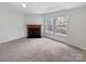 Open living room featuring a fireplace, natural light from two windows, and plush carpeting at 1121 Swearngan Ridge Ct, Charlotte, NC 28216