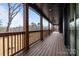 Relaxing covered porch with wood railings, natural lighting, and views of wooded yard at 123 Mills Garden Rd, Statesville, NC 28625
