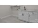 Bright laundry room features gray tile flooring, white cabinets, and modern matte black fixtures at 123 Mills Garden Rd, Statesville, NC 28625