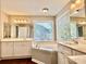 Spacious primary bathroom with dual sinks, soaking tub, and large windows with wooded view at 12403 Panthersville Dr, Charlotte, NC 28269