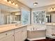 Bright bathroom with dual sinks, soaking tub, and large windows with wooded view at 12403 Panthersville Dr, Charlotte, NC 28269