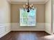 Dining room featuring a modern chandelier, wainscoting, and dark hardwood flooring and natural light at 12403 Panthersville Dr, Charlotte, NC 28269