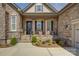 Covered front porch featuring stone pillars, two chairs, and lush landscaping at 14830 Creeks Edge Dr, Charlotte, NC 28278