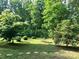 Landscaped backyard featuring various trees and bushes around a fire pit area at 1496 Givens St, Hickory, NC 28602