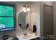Well-lit bathroom with a modern round mirror, vanity, and a bright window overlooking outdoor greenery at 1496 Givens St, Hickory, NC 28602
