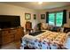 Well-lit main bedroom features a bed with a quilt, dresser, seating area, and a view of the outside at 1496 Givens St, Hickory, NC 28602