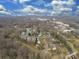 Expansive aerial view of a neighborhood with mature trees and a distant city skyline under a partly cloudy sky at 5300 Buckingham Dr, Charlotte, NC 28209