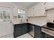 A well-lit kitchen showcasing gray and white cabinetry, stainless steel appliances, and white tile flooring at 5300 Buckingham Dr, Charlotte, NC 28209