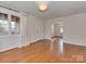 Bright living room with gleaming hardwood floors, soft curtains, and an open doorway at 5300 Buckingham Dr, Charlotte, NC 28209