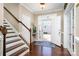 Welcoming foyer featuring hardwood floors, staircase with white risers, and natural light streaming through the front door at 6187 Cloverdale Dr, Tega Cay, SC 29708