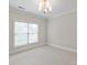 Bright bedroom features a window with blinds and a stylish chandelier at 7924 Pemswood St, Charlotte, NC 28277