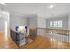 Upstairs landing featuring hardwood floors, wood railing, and a view of a window at 7924 Pemswood St, Charlotte, NC 28277