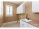 Well-lit laundry room with ample storage cabinets, a sink, and a window at 7924 Pemswood St, Charlotte, NC 28277