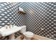 Close-up of a stylish powder room featuring unique wallpaper and a pedestal sink at 7924 Pemswood St, Charlotte, NC 28277