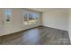 Empty living room with wood-look floors, fresh white walls, and ample natural light from the large front window at 8103 Idlewild Rd, Indian Trail, NC 28079