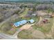 Overhead view of a home with a blue roof, outbuildings, and an expansive wooded and open landscape at 836 Love Rd, Blackstock, SC 29014