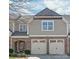 Charming townhome featuring a brick facade, a welcoming entrance, and a two-car garage with carriage-style doors at 8513 Loxton Cir, Charlotte, NC 28214