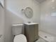 Clean bathroom with a toilet, vanity, round mirror, and white tiled shower at 924 Springdale Ln, Gastonia, NC 28052