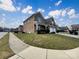 Elegant brick home with a manicured lawn, and a side-entry garage under a vibrant blue sky with scattered clouds at 9503 Rocky Spring Nw Ct, Concord, NC 28027