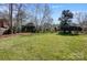 Green backyard featuring well-maintained lawn, mature trees, and a wooden fence at 10207 Rattersly Ct, Charlotte, NC 28277