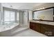 Main bathroom featuring a glass shower, soaking tub, dual sink vanity, and a chandelier at 10207 Rattersly Ct, Charlotte, NC 28277