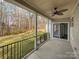Relax on this covered patio with fan and railing overlooking a wooded backyard, perfect for outdoor enjoyment and privacy at 1210 Aragon Beach Rd, Rock Hill, SC 29732