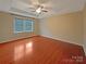 Spacious bedroom featuring hardwood floors, a tray ceiling with a fan, and a window showcasing the outdoors at 13217 Reunion St, Charlotte, NC 28278