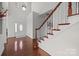 Bright foyer with hardwood floors, staircase with white spindles and wood railing, and a front door with glass detailing at 15323 Prescott Hill Ave, Charlotte, NC 28277