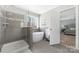 Modern bathroom showcasing tiled walk-in shower and separate soaking tub with large window at 16110 Foreleigh Rd, Huntersville, NC 28078
