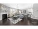 Spacious living room with a fireplace, modern furniture, and a view into the dining area and kitchen at 16110 Foreleigh Rd, Huntersville, NC 28078